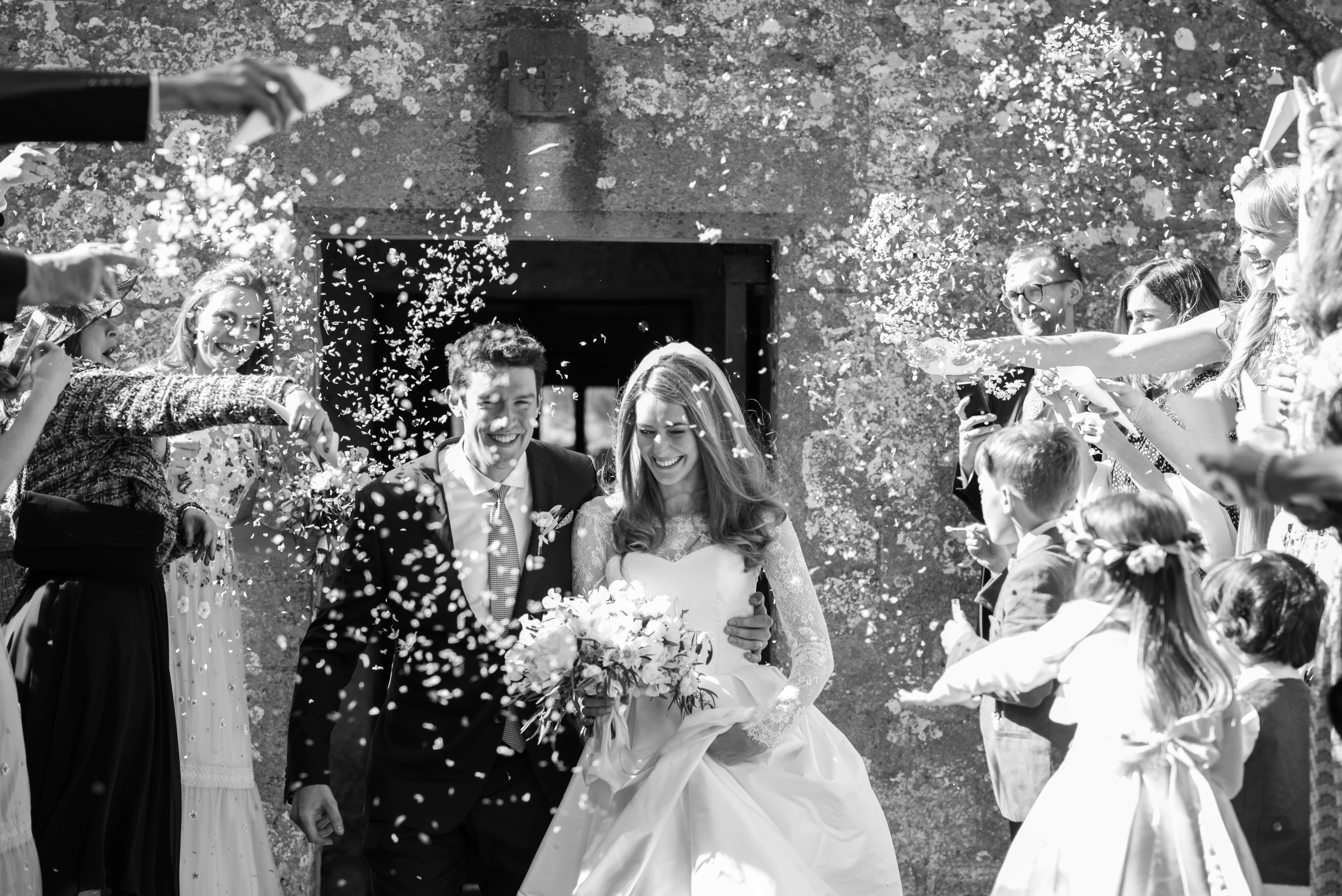 bride and groom with confetti outside the church in dorset